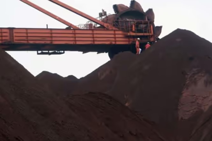 Workers are seen on the top of an iron ore pile as a machine works on blending the iron ore, at Dalian Port, Liaoning province, China. (Reuters Photo)